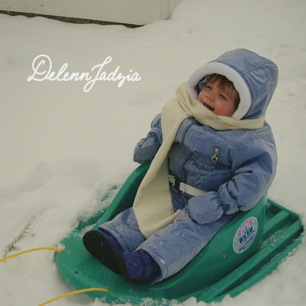 A baby sits in a snowsuit in the snow